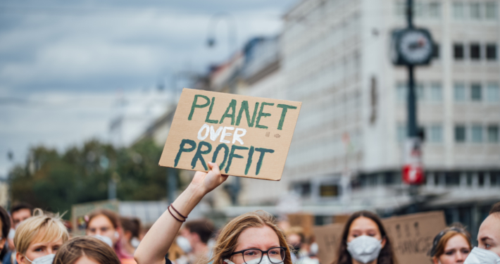 Protester holding a banner with a message "Planet over profit"