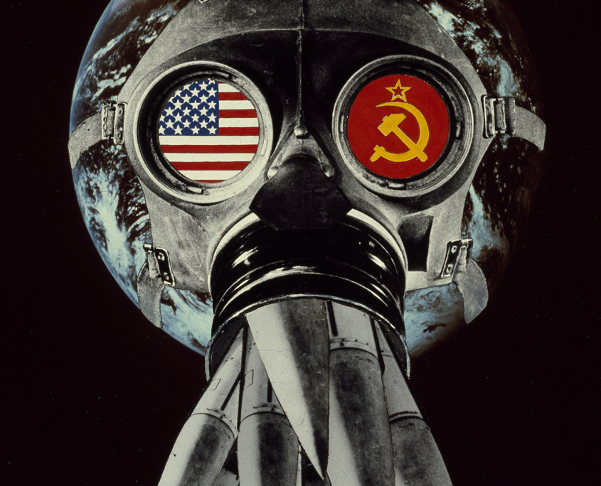 Weltkugel mit Gasmaske auf, in deren Augengläsern die Flaggen der USA links, die der Sowjetunion rechts zu sehen sind. Anstatt des Mundfilters ragen dort Nuklearsprengköpfe heraus.