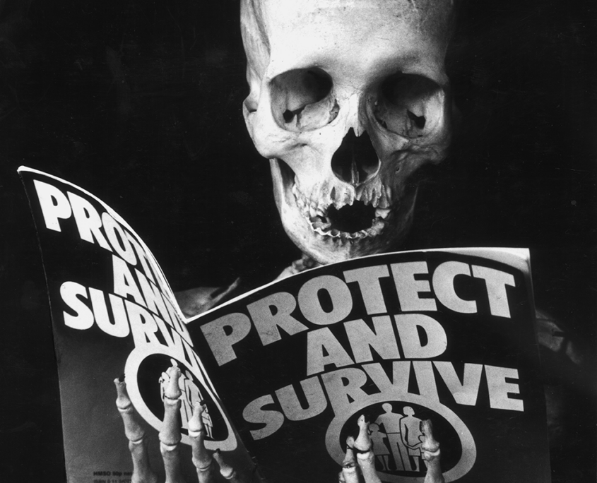 Ein Skelett liest die Infobroschüre der britischen Regierung zum Verhalten im Falle eines Atomschlags "Protect and Survive"